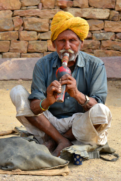 a man with a yellow turban sitting on the ground
