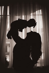 a silhouette of a woman holding a baby in her arms