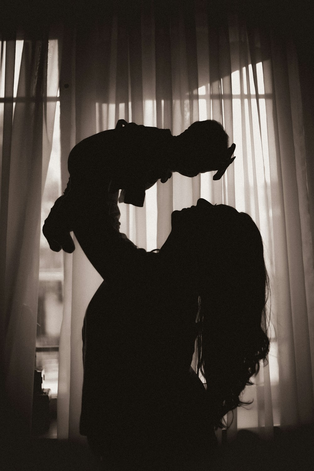 a silhouette of a woman holding a baby in her arms