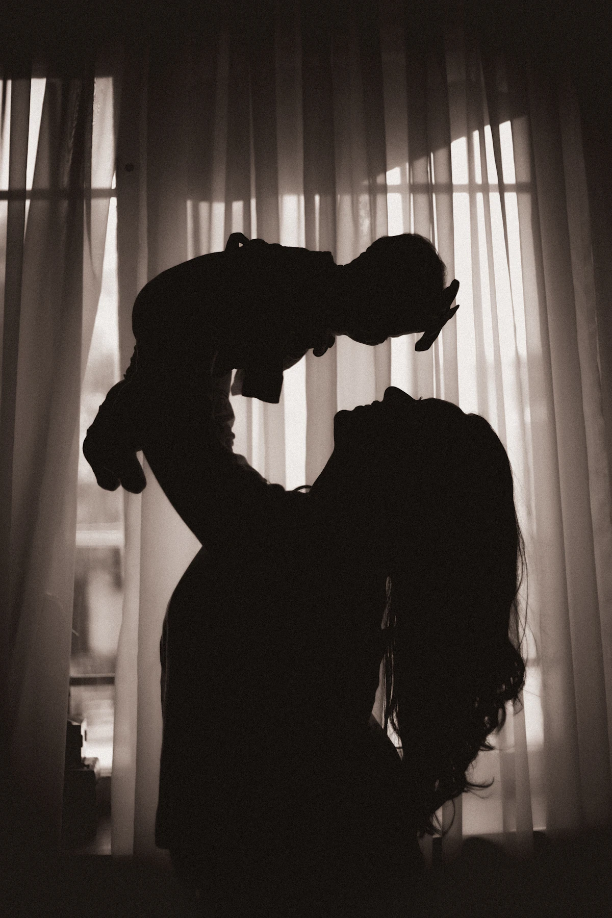 Silhouette of a woman tenderly holding a baby