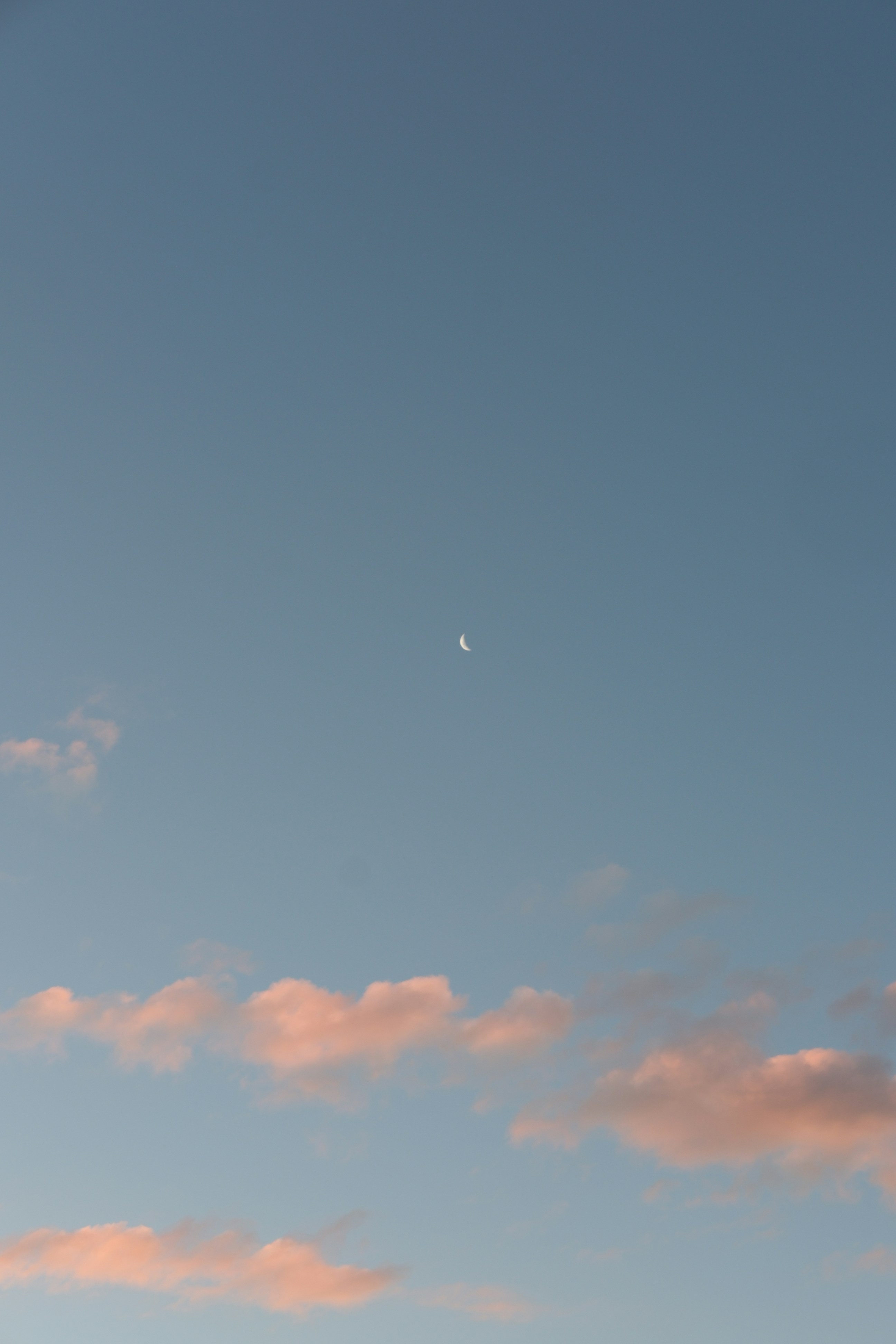 a plane flying in the sky with the moon in the distance