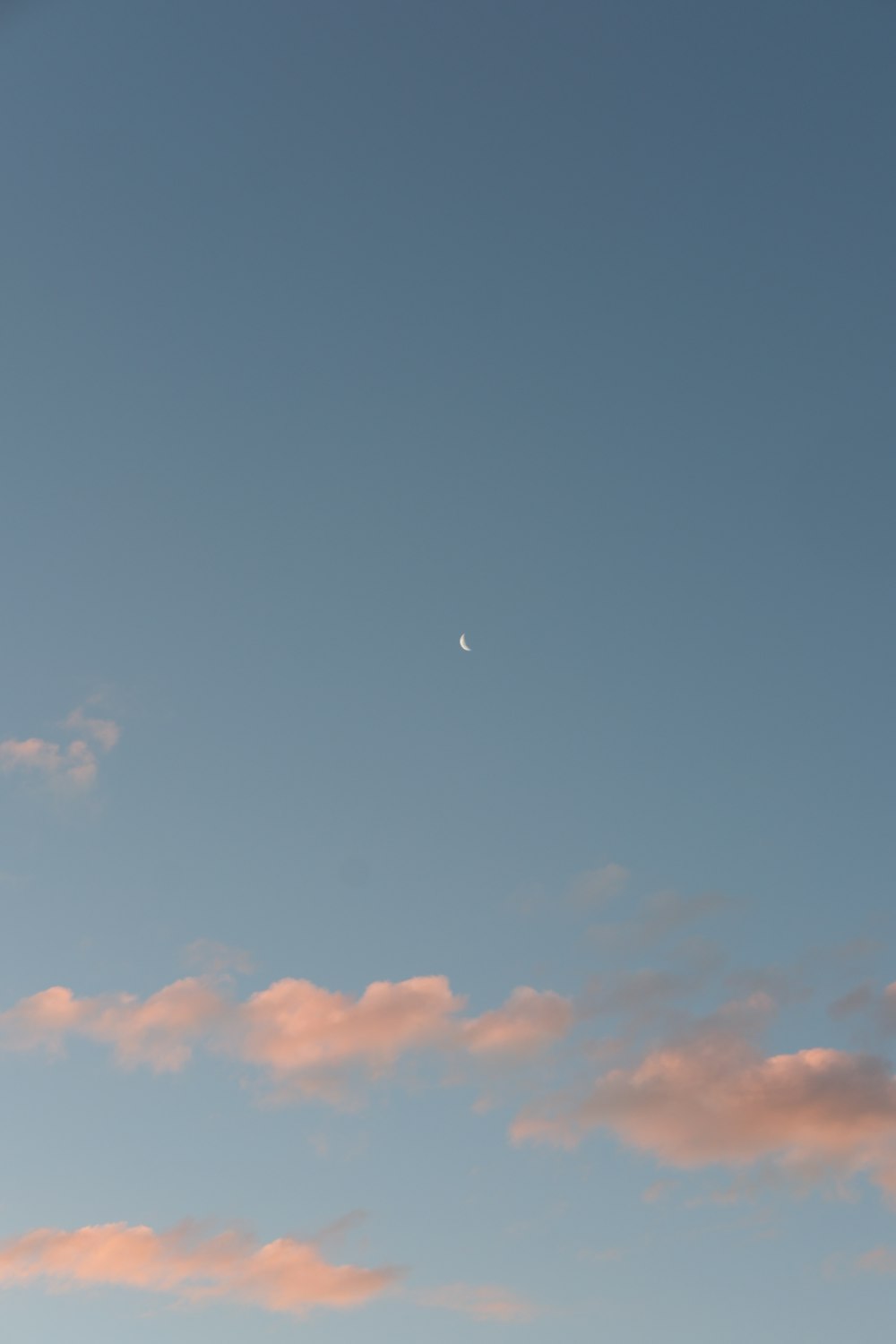 a plane flying in the sky with the moon in the distance