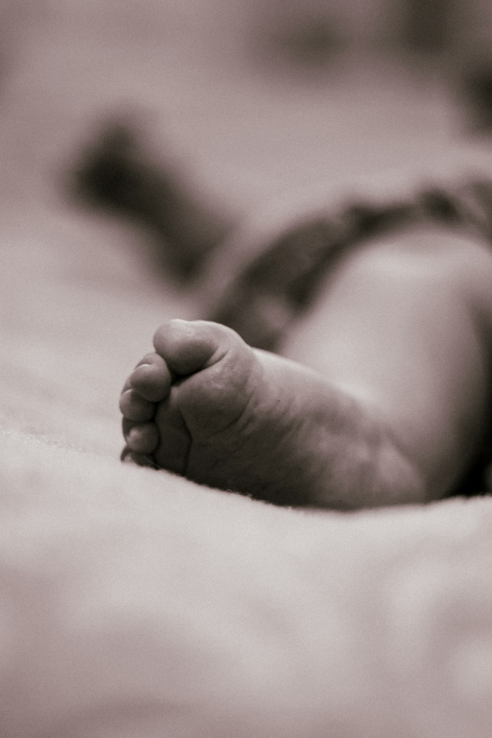 a black and white photo of a baby laying on a bed