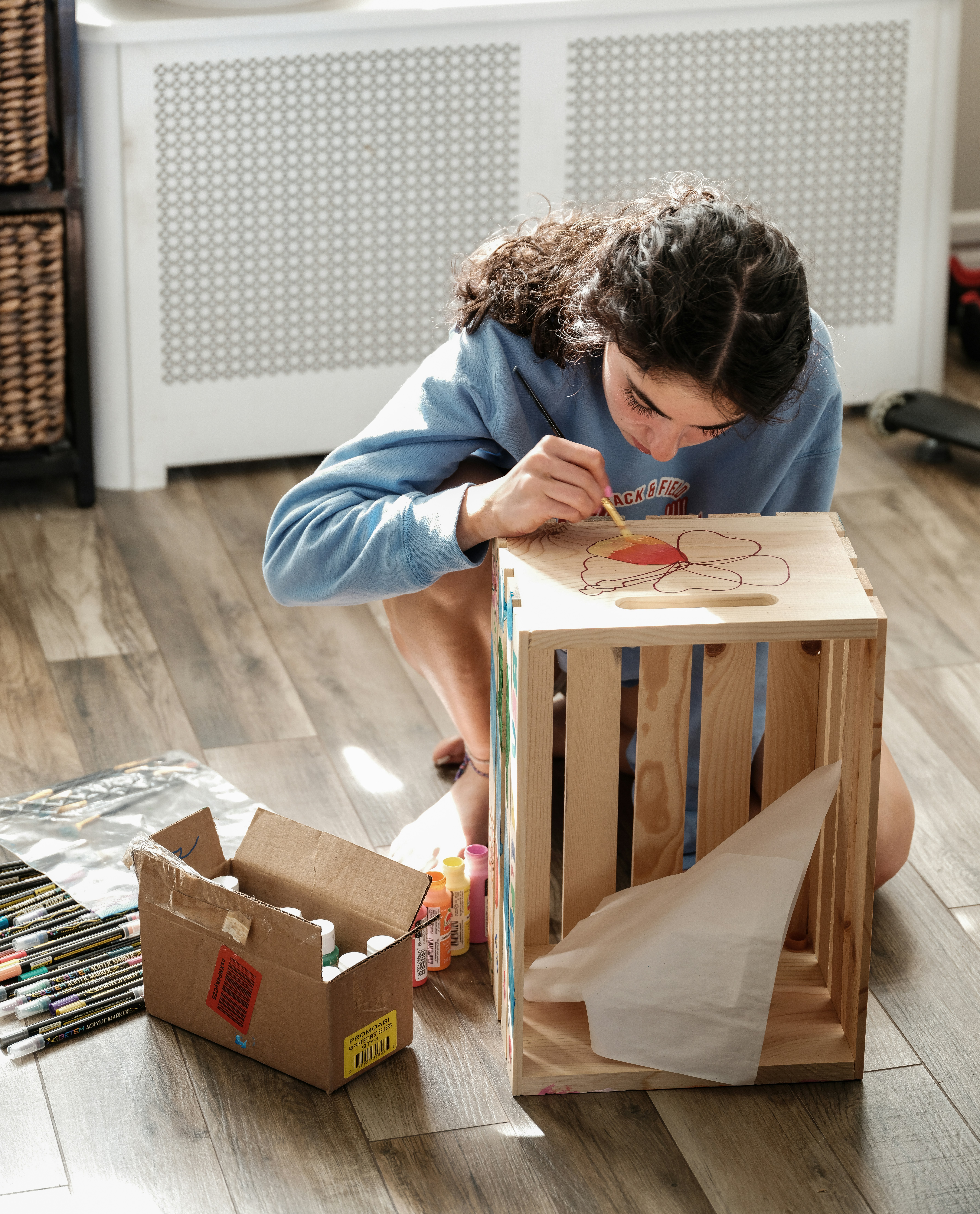 a woman sitting on the floor next to a wooden box