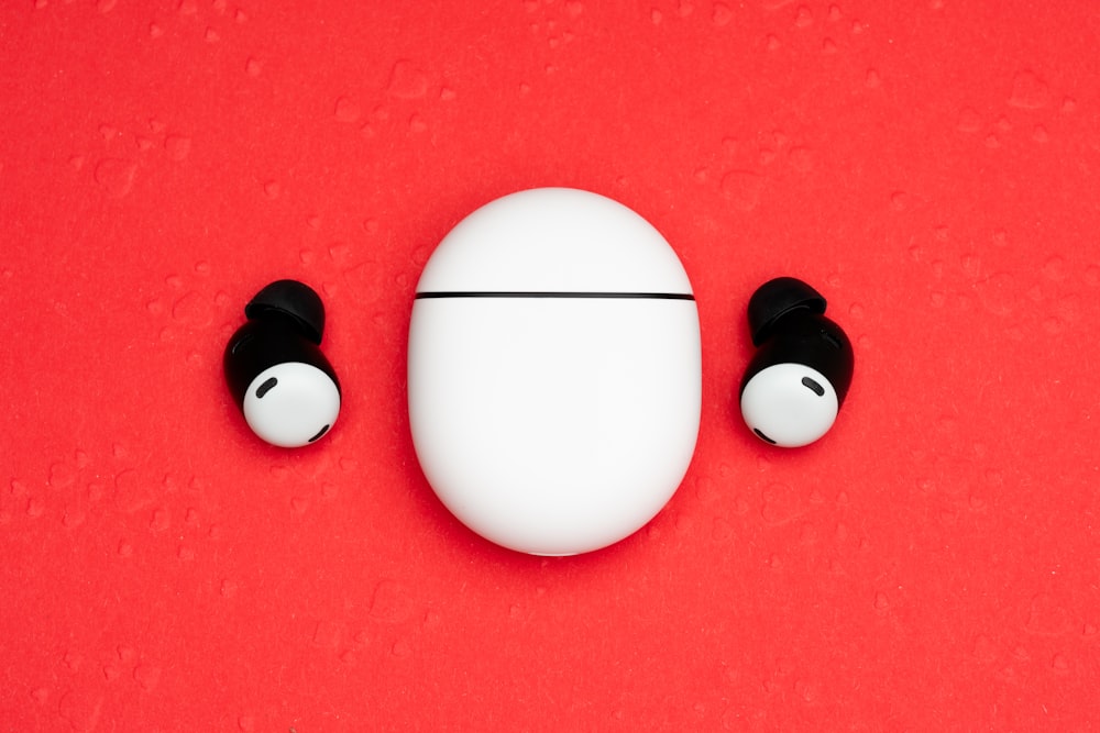a pair of ear buds sitting on top of a red surface