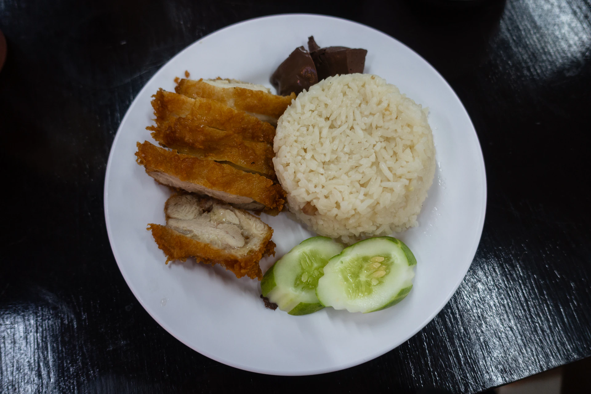 a white plate topped with rice, meat and cucumbers