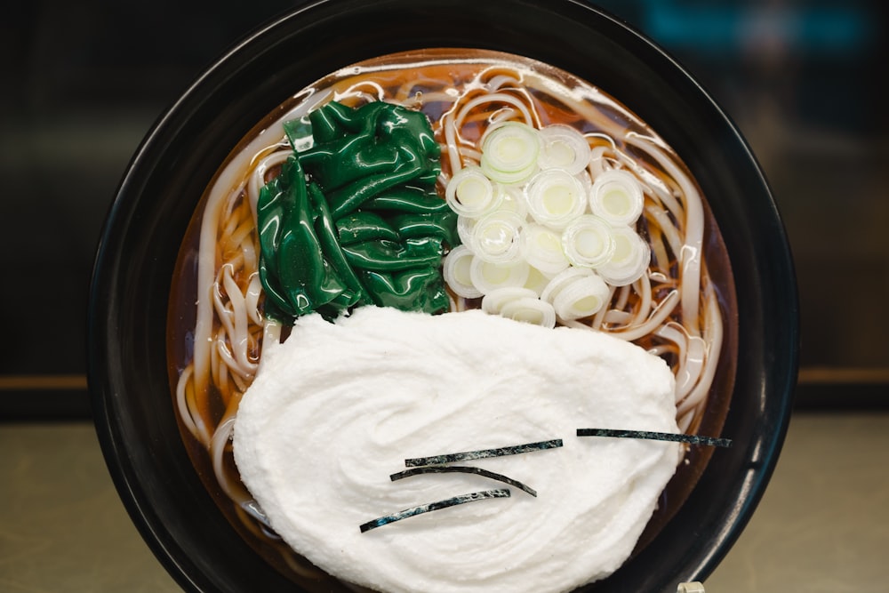 a bowl of noodles and vegetables with chopsticks