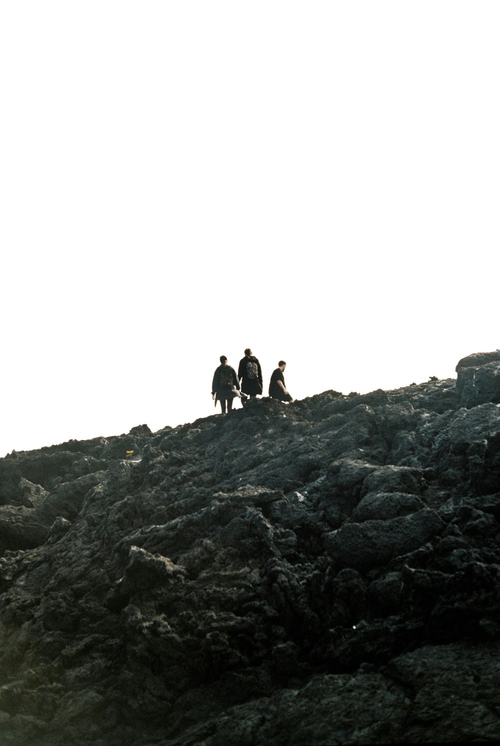 a group of people sitting on top of a rocky hill