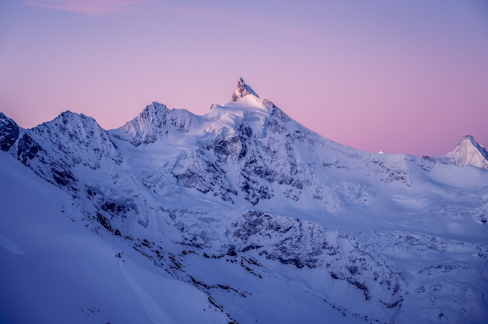 a snow covered mountain with a pink sky in the background