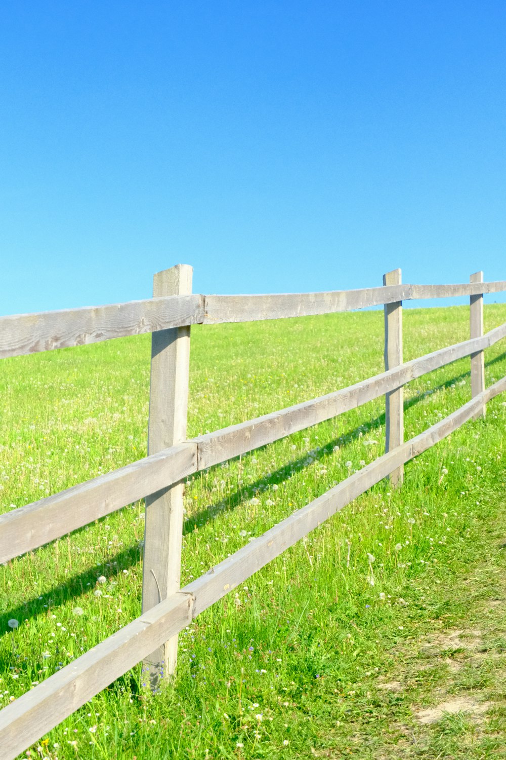 a wooden fence in the middle of a grassy field