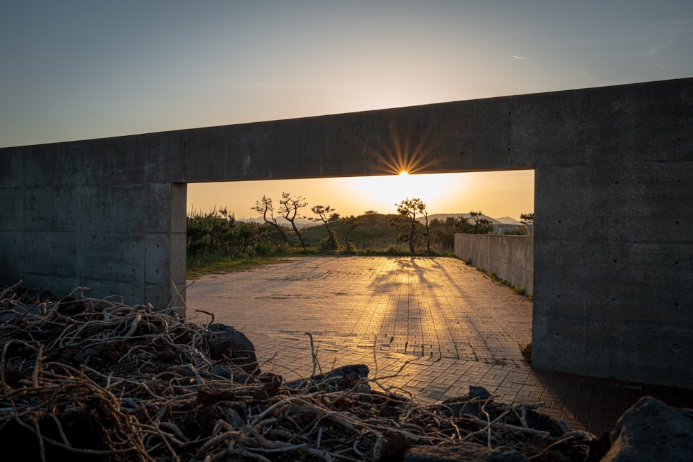 the sun is setting behind a concrete arch