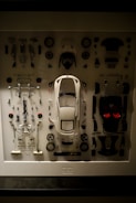 a display case with a white car surrounded by assorted parts