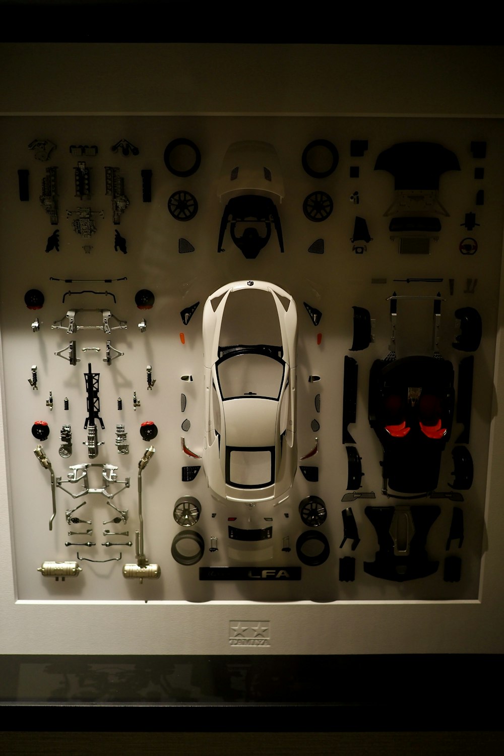 a display case with a white car surrounded by assorted parts