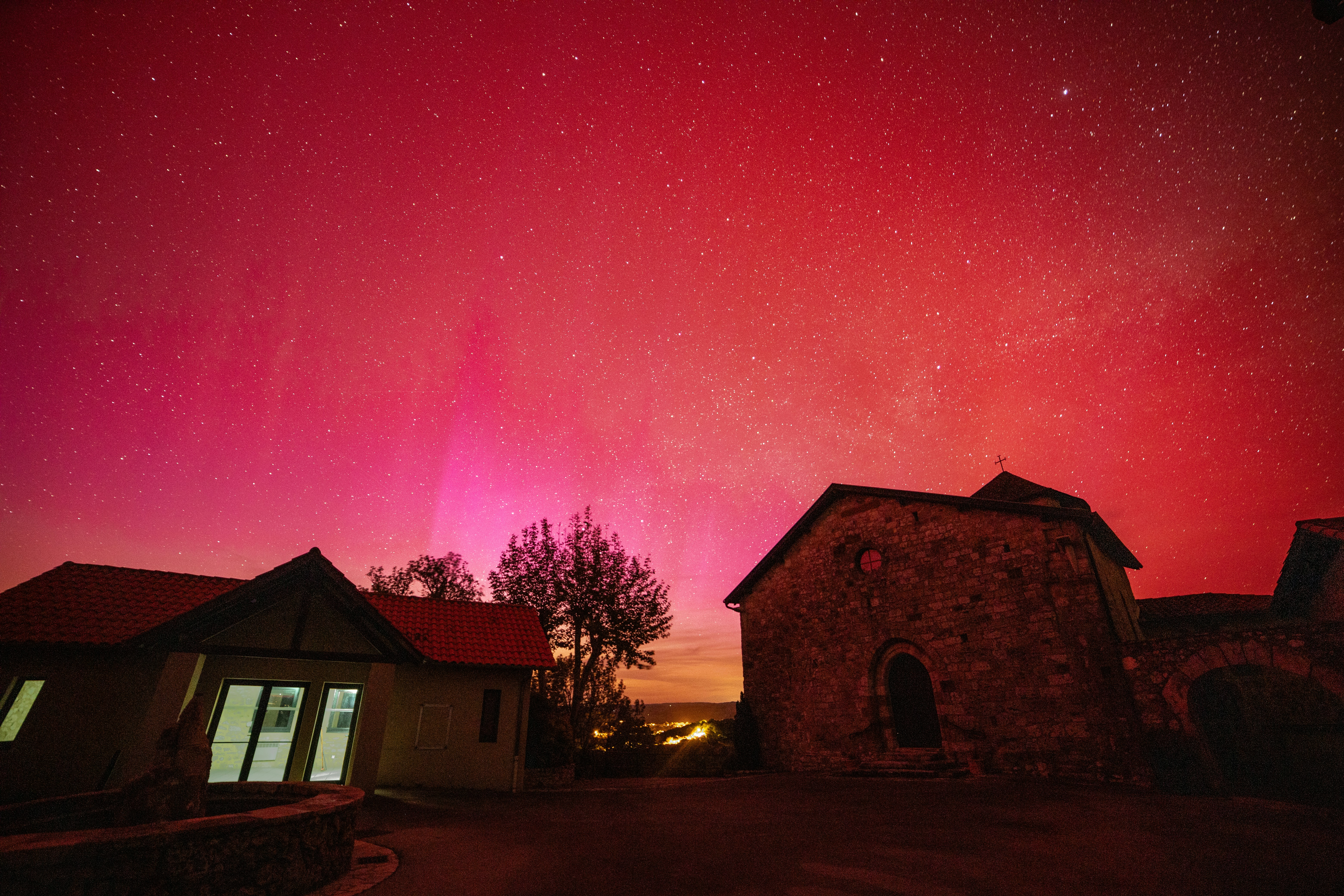 a red and purple sky with a house and trees