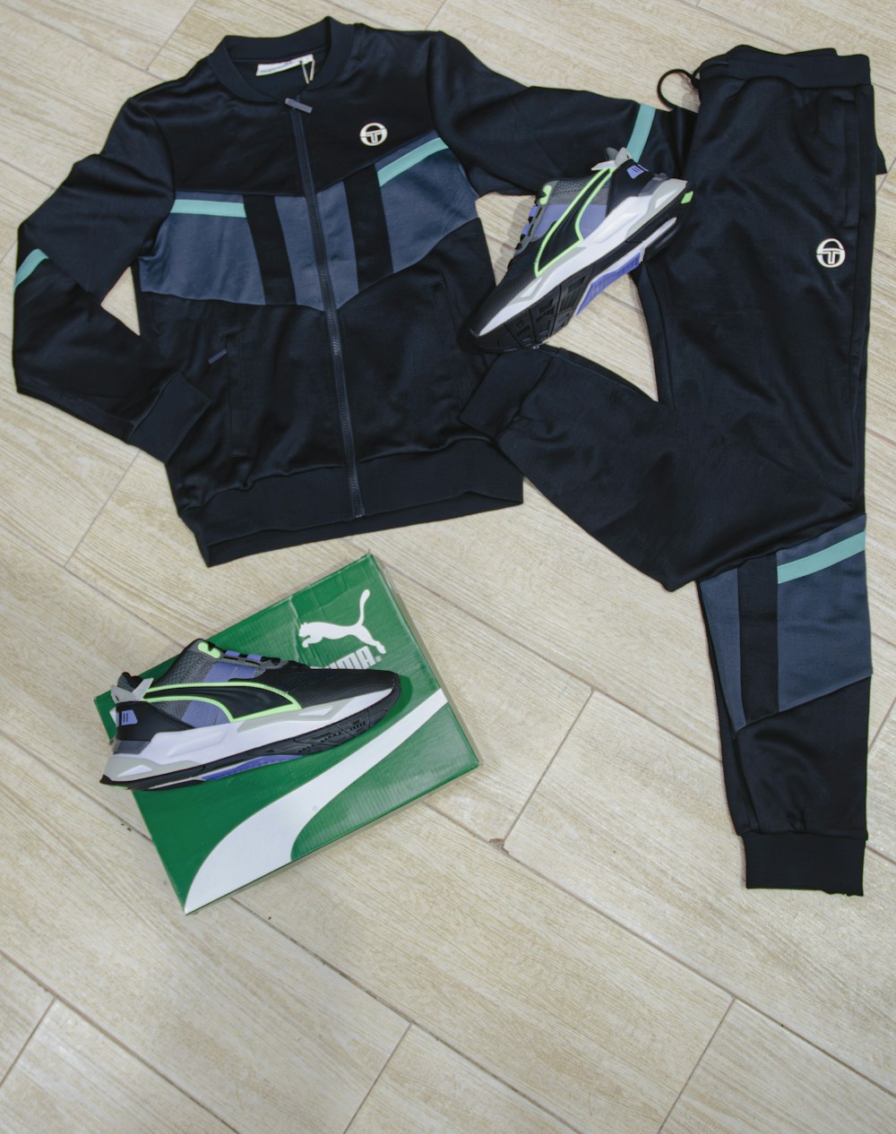 a pair of black and blue tracksuits sitting on a wooden floor