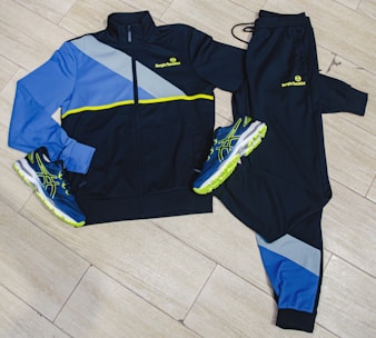 a pair of tracksuits and a pair of running shoes on a wooden floor