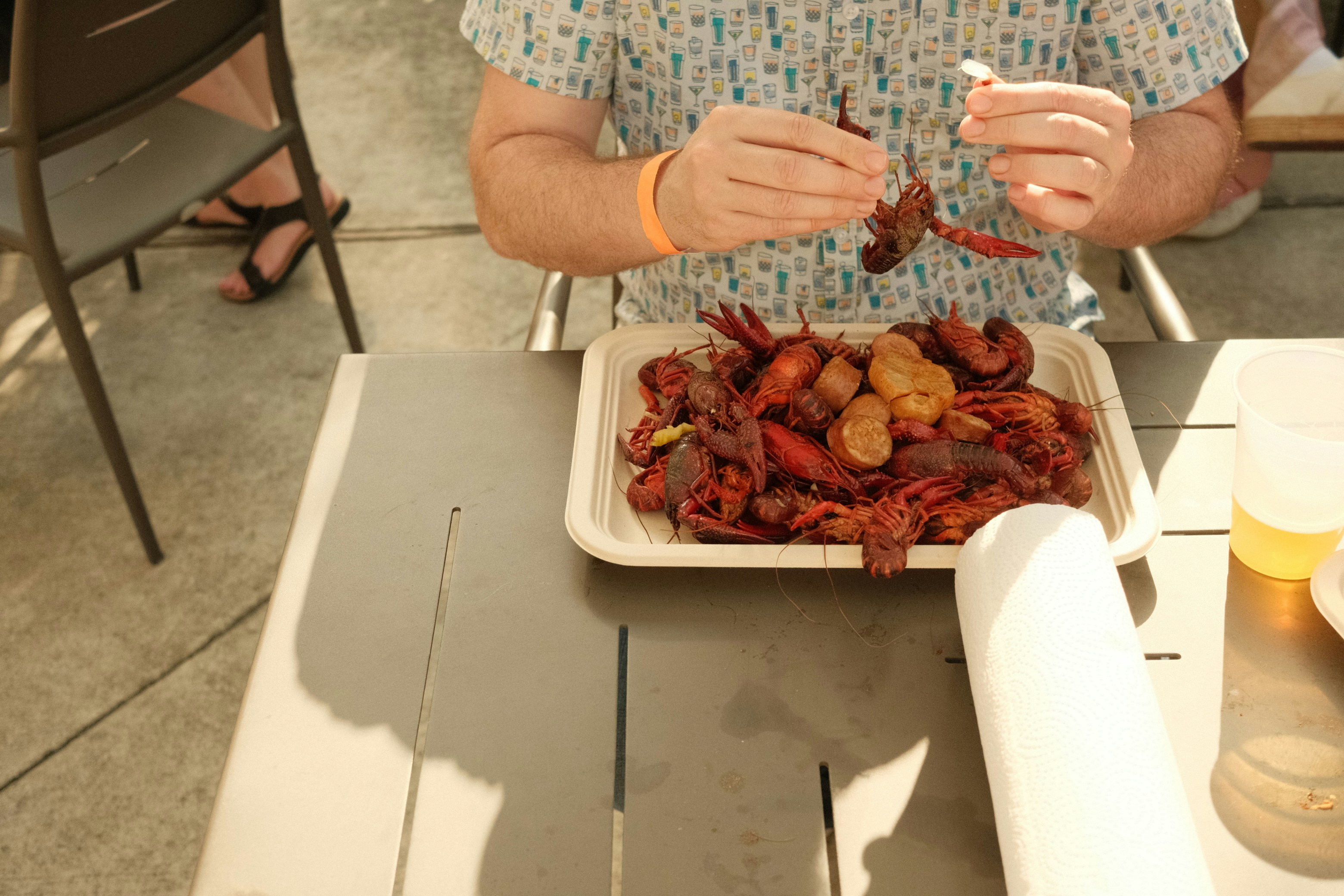 a man sitting at a table with a plate of food, crawfish boil