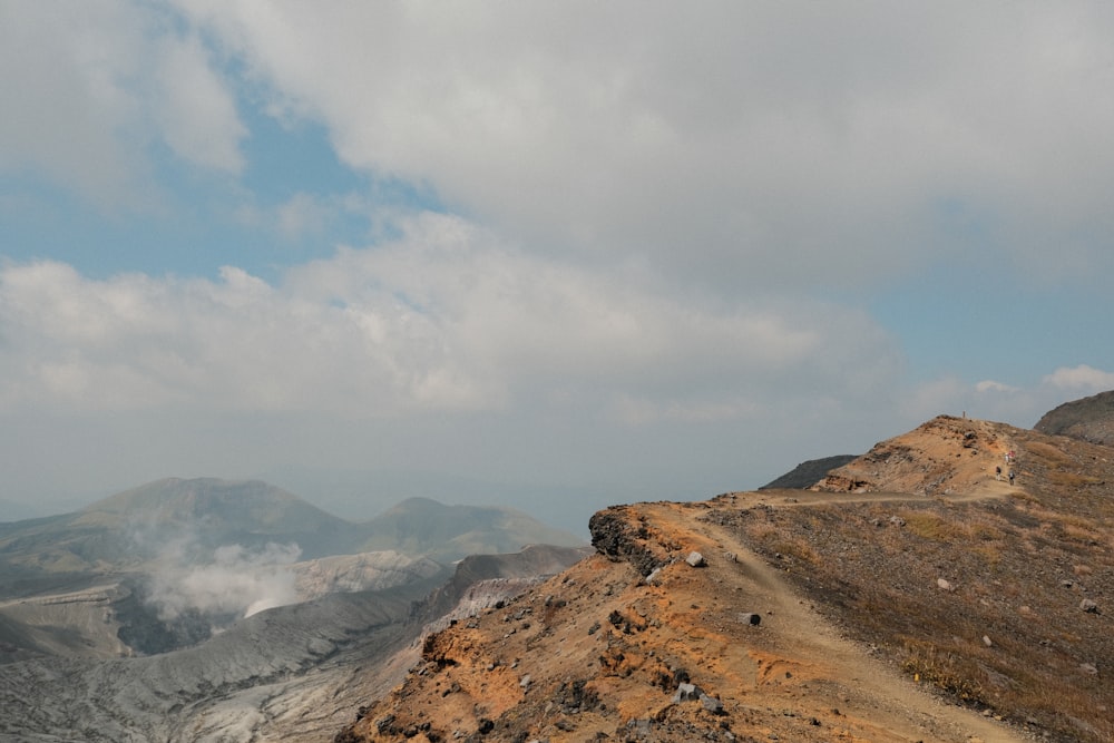 a dirt road on a hill with mountains in the background