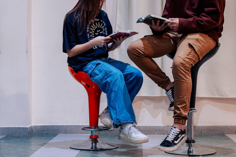 a couple of people sitting on top of a red chair