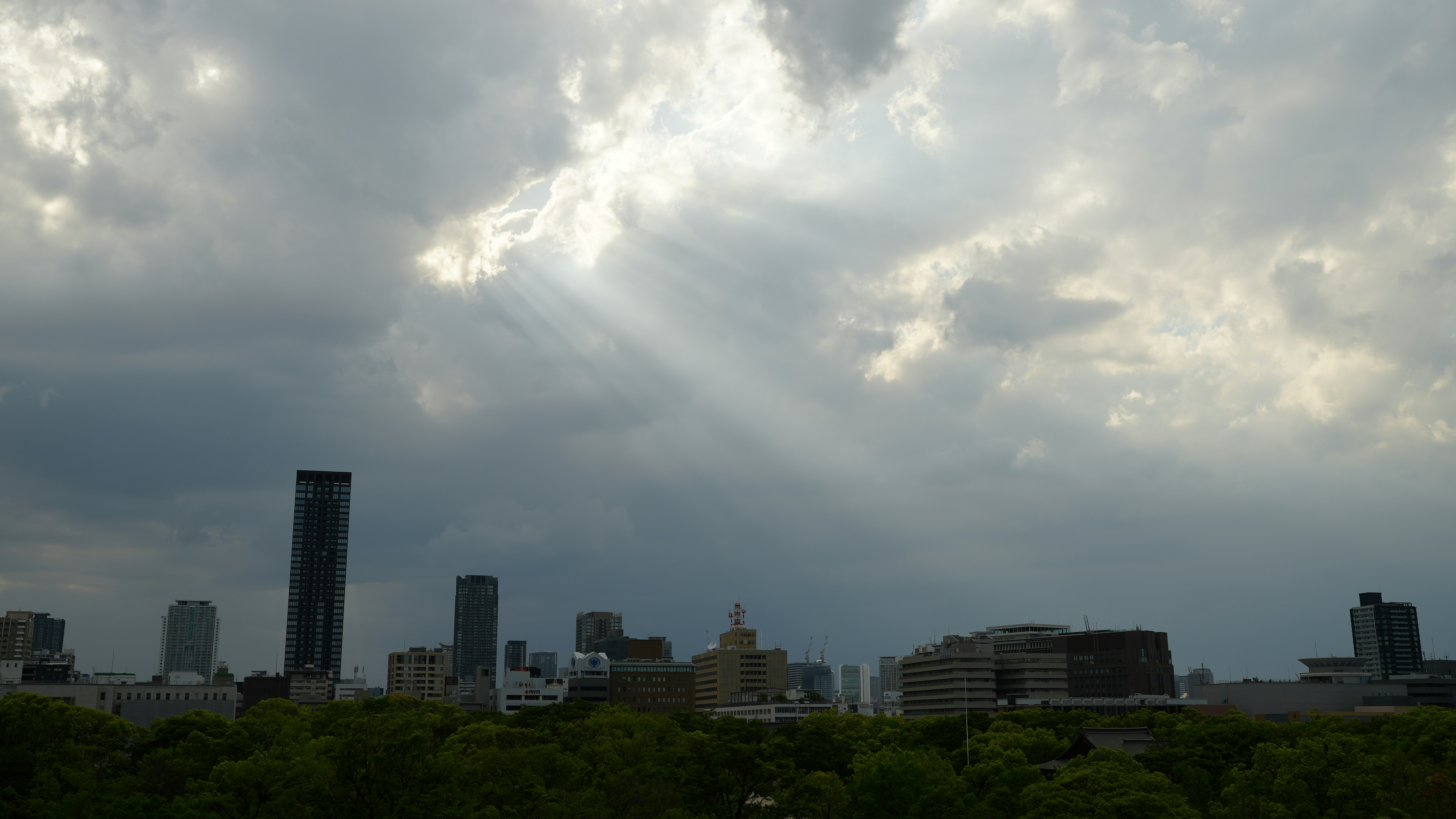 a cloudy sky over a city with buildings and trees