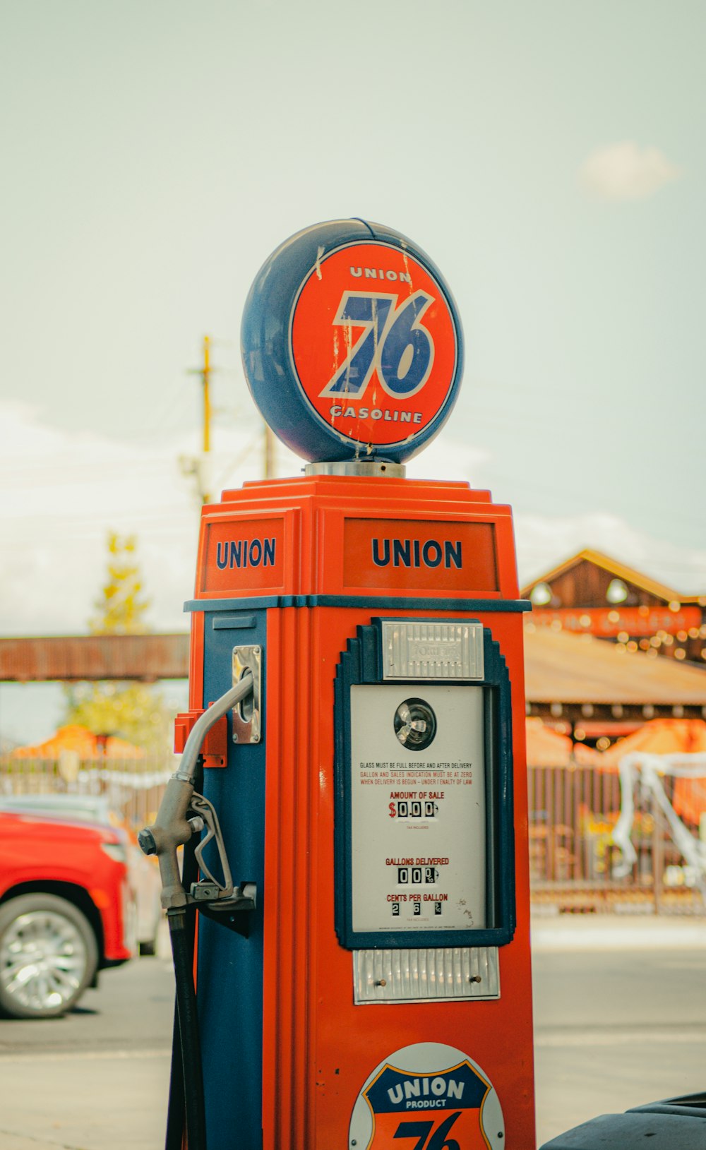 an orange and blue gas pump sitting on the side of a road