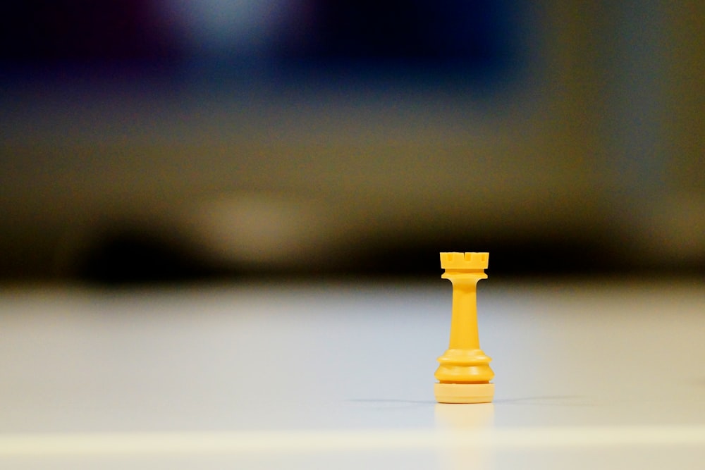 a yellow chess piece sitting on top of a white table