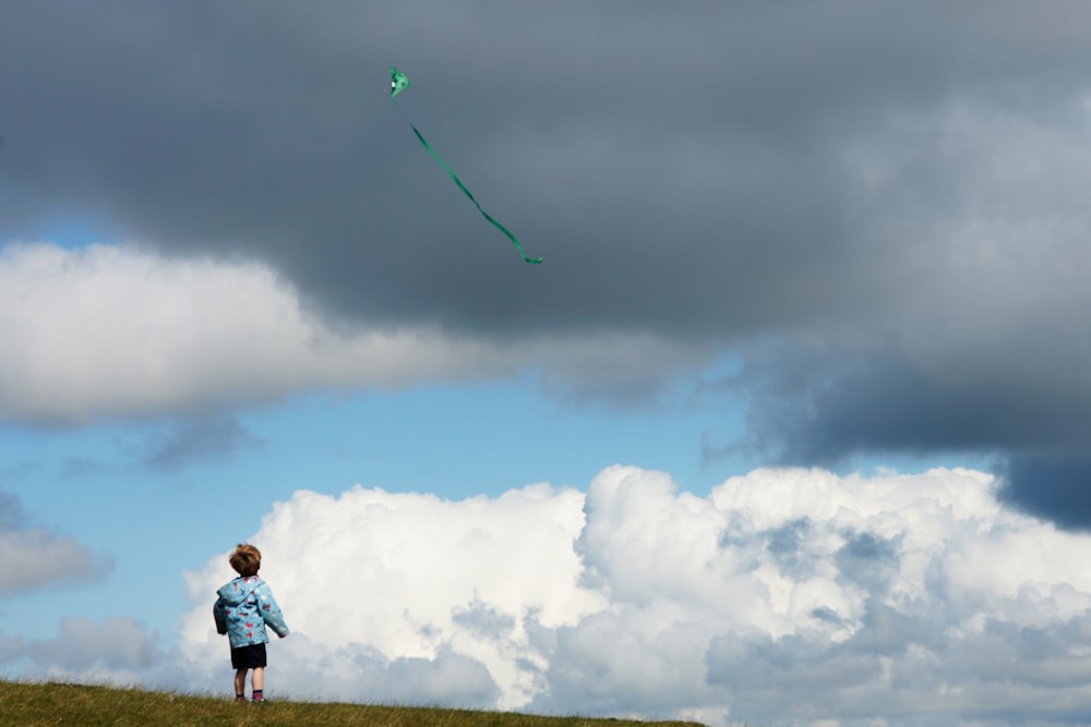 a person standing on a hill flying a kite