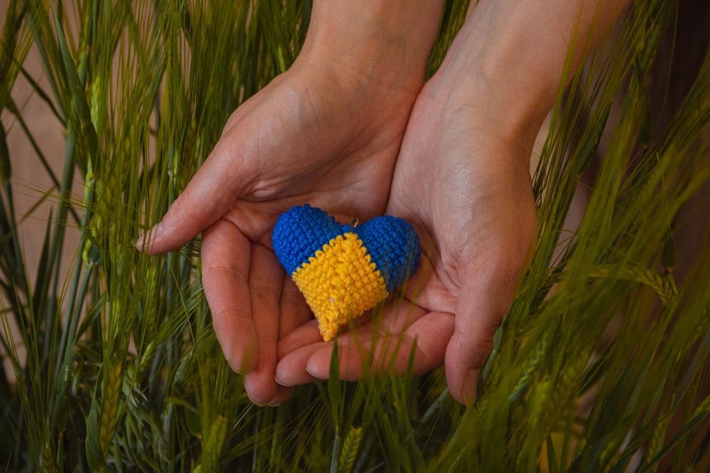 a person holding a small crocheted heart in their hands