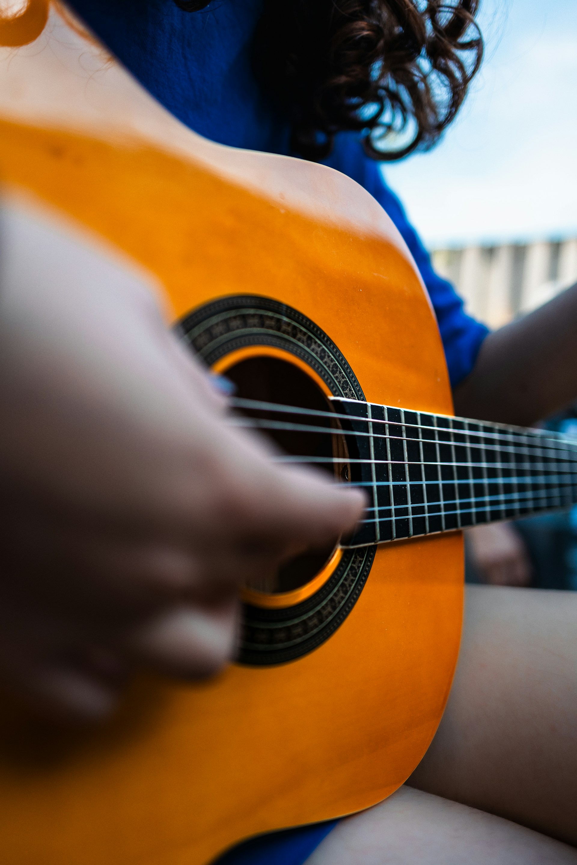 a woman is playing a guitar outside on a sunny day