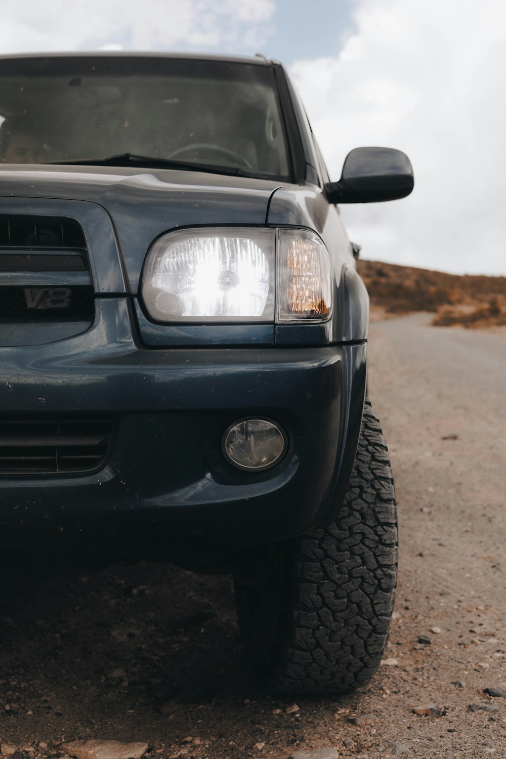 the front end of a truck parked on a dirt road