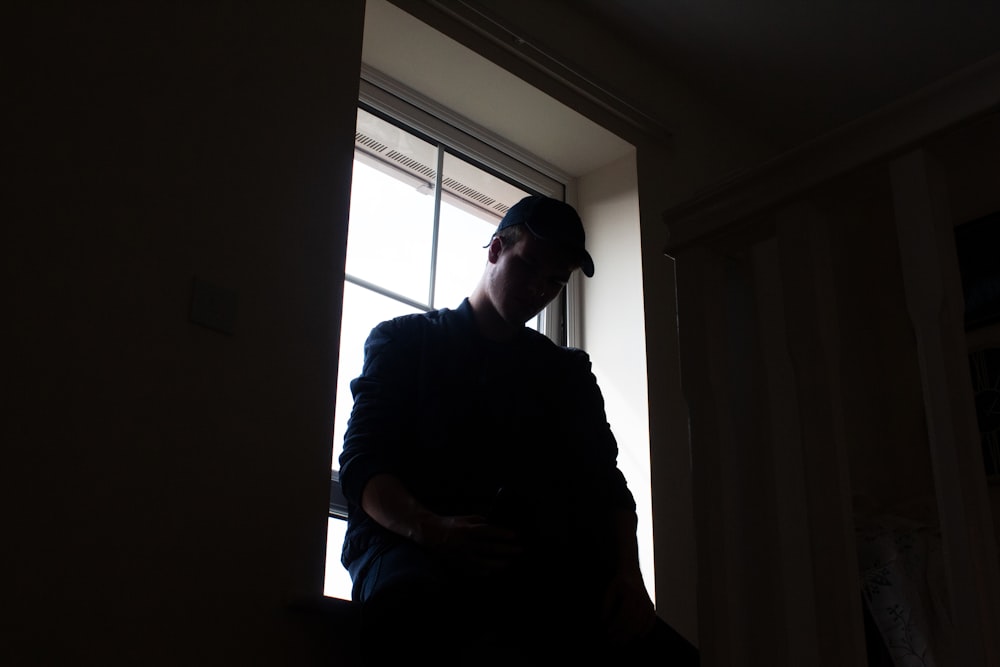 a man standing in front of a window in a dark room