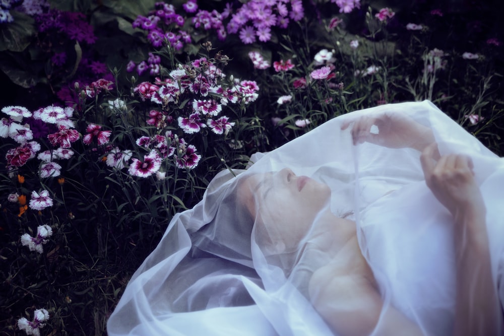 a woman laying in a field of flowers