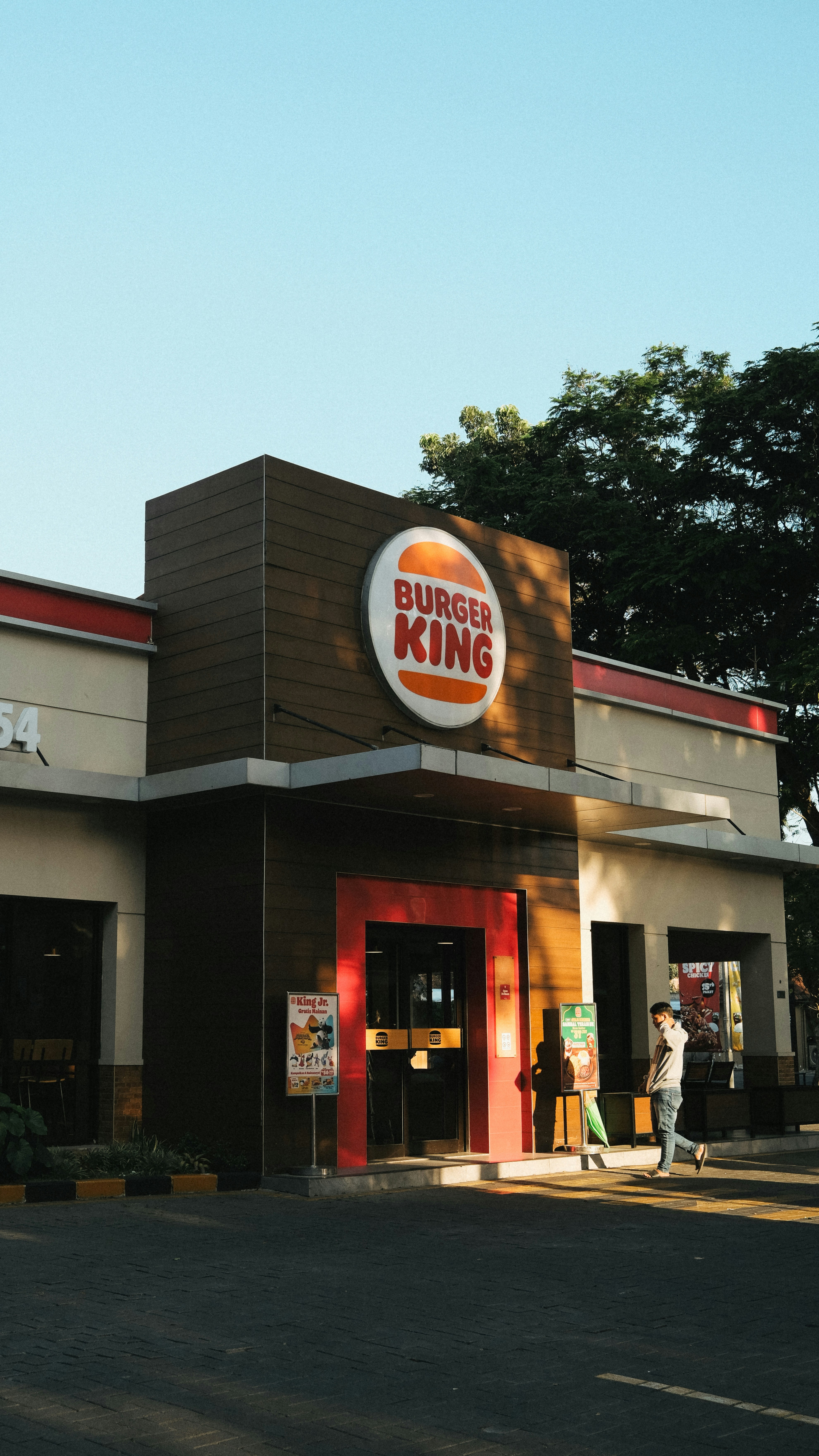 a burger king restaurant with a man standing outside