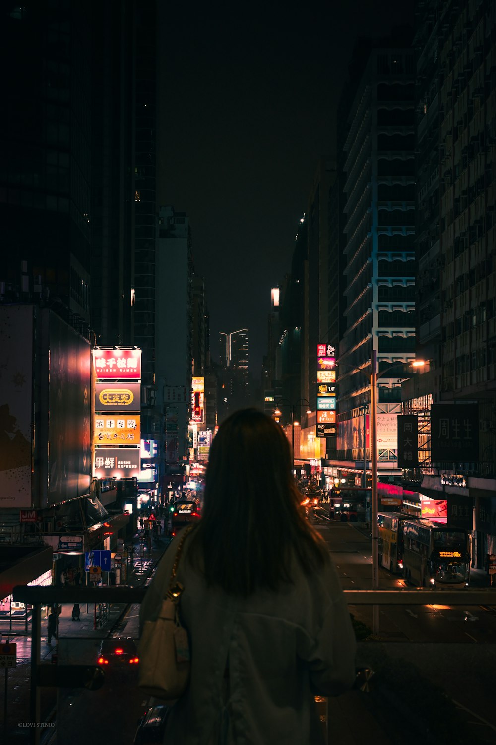 a woman standing in the middle of a city at night