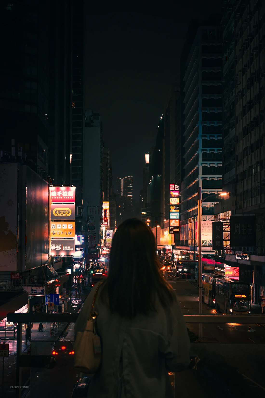 A woman standing alone in the middle of the city at night