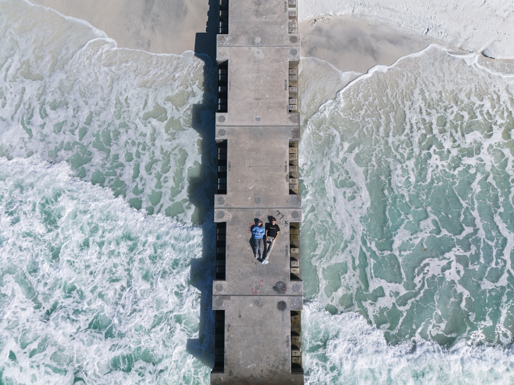 an aerial view of a pier with two people on it