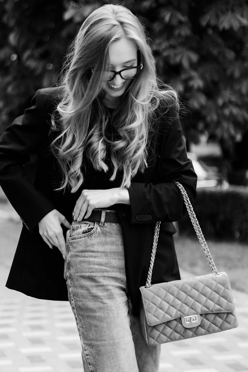 a woman in a black jacket and jeans holding a chanel bag