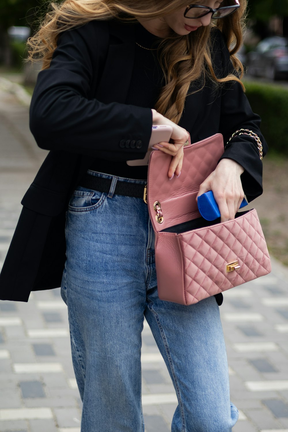 a woman holding a pink purse and a cell phone