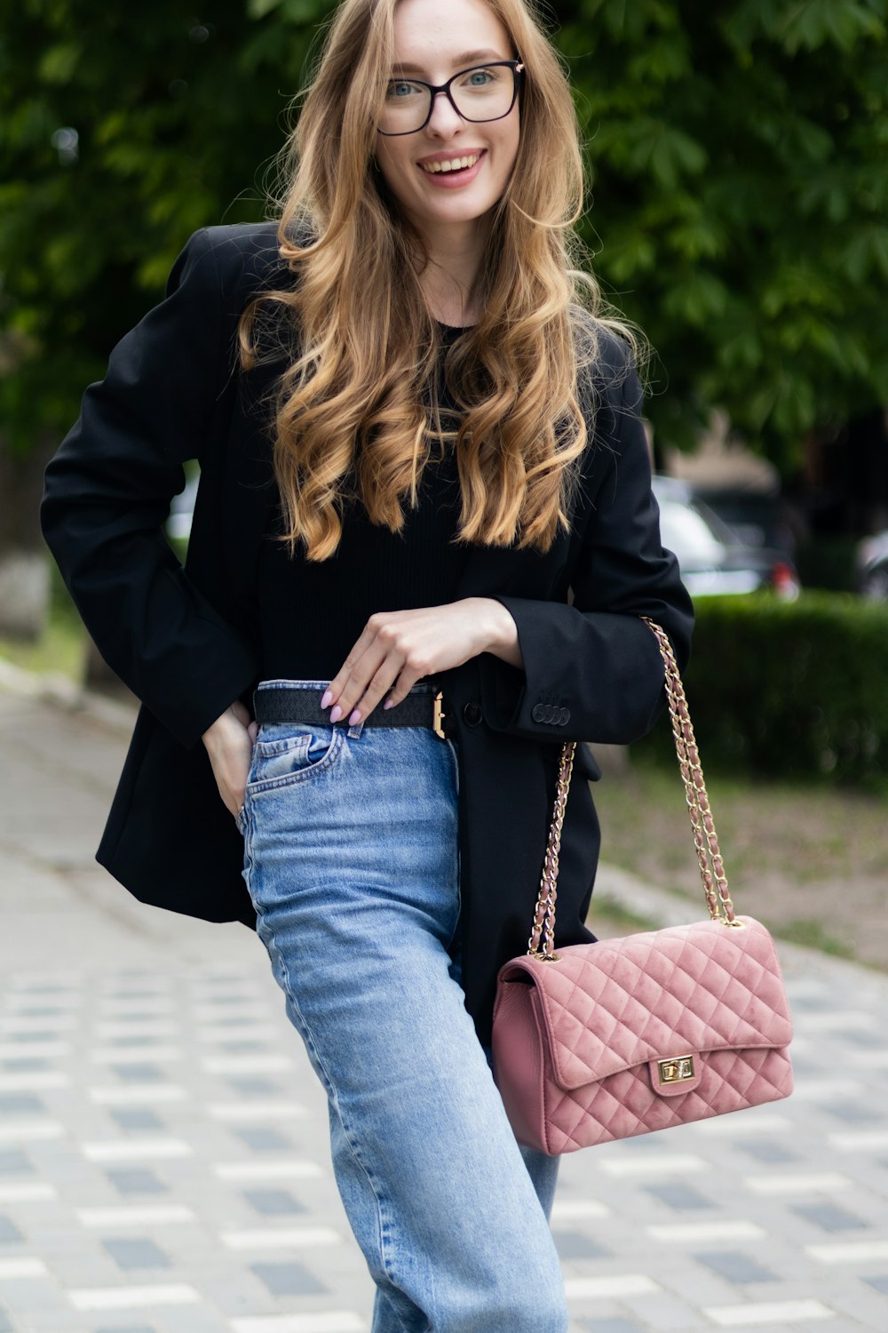 a woman in black jacket and jeans holding a pink purse