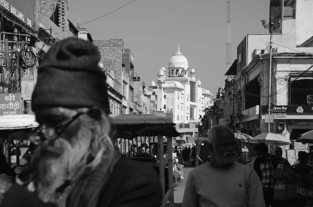 a group of people walking down a street next to tall buildings