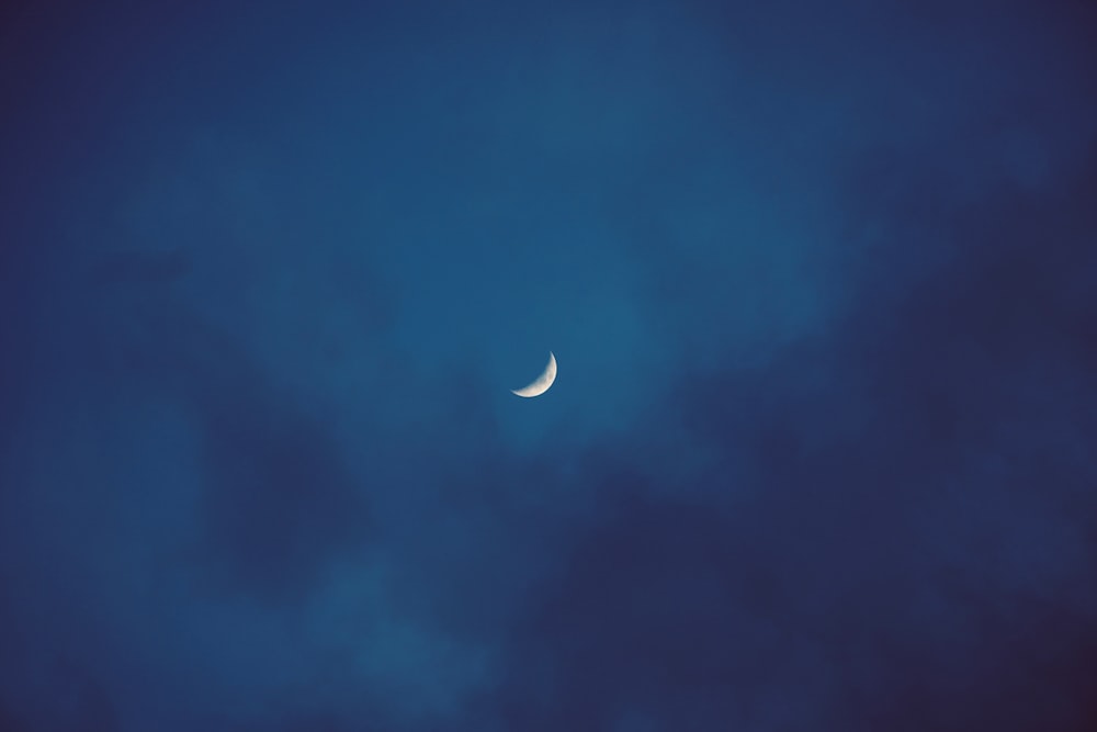 a half moon in a cloudy sky with a few clouds