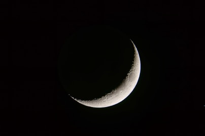 a half moon is seen in the dark sky