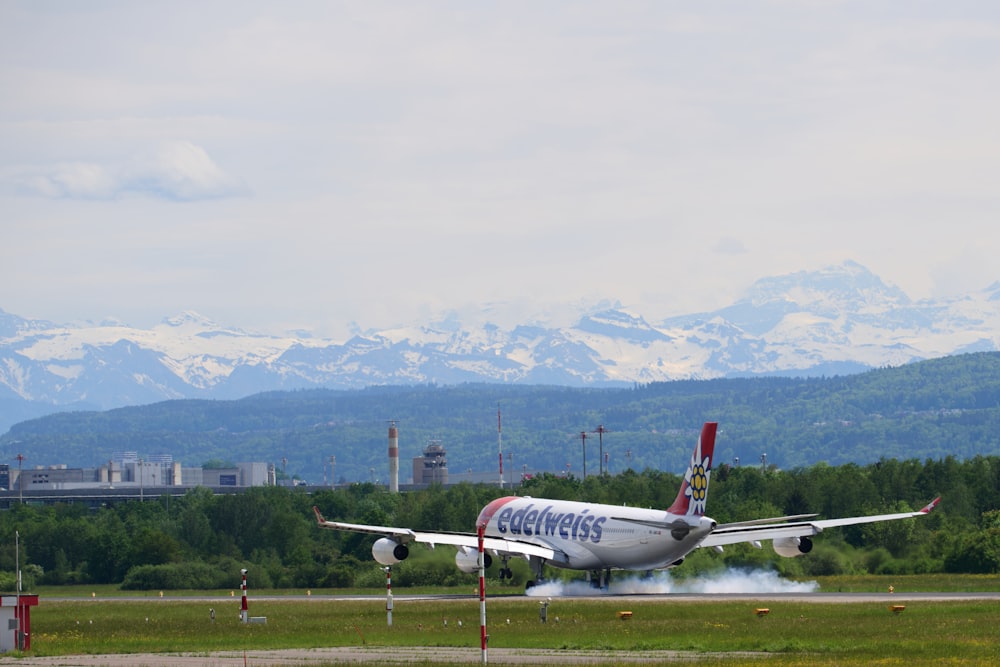 a plane on a runway with mountains in the background