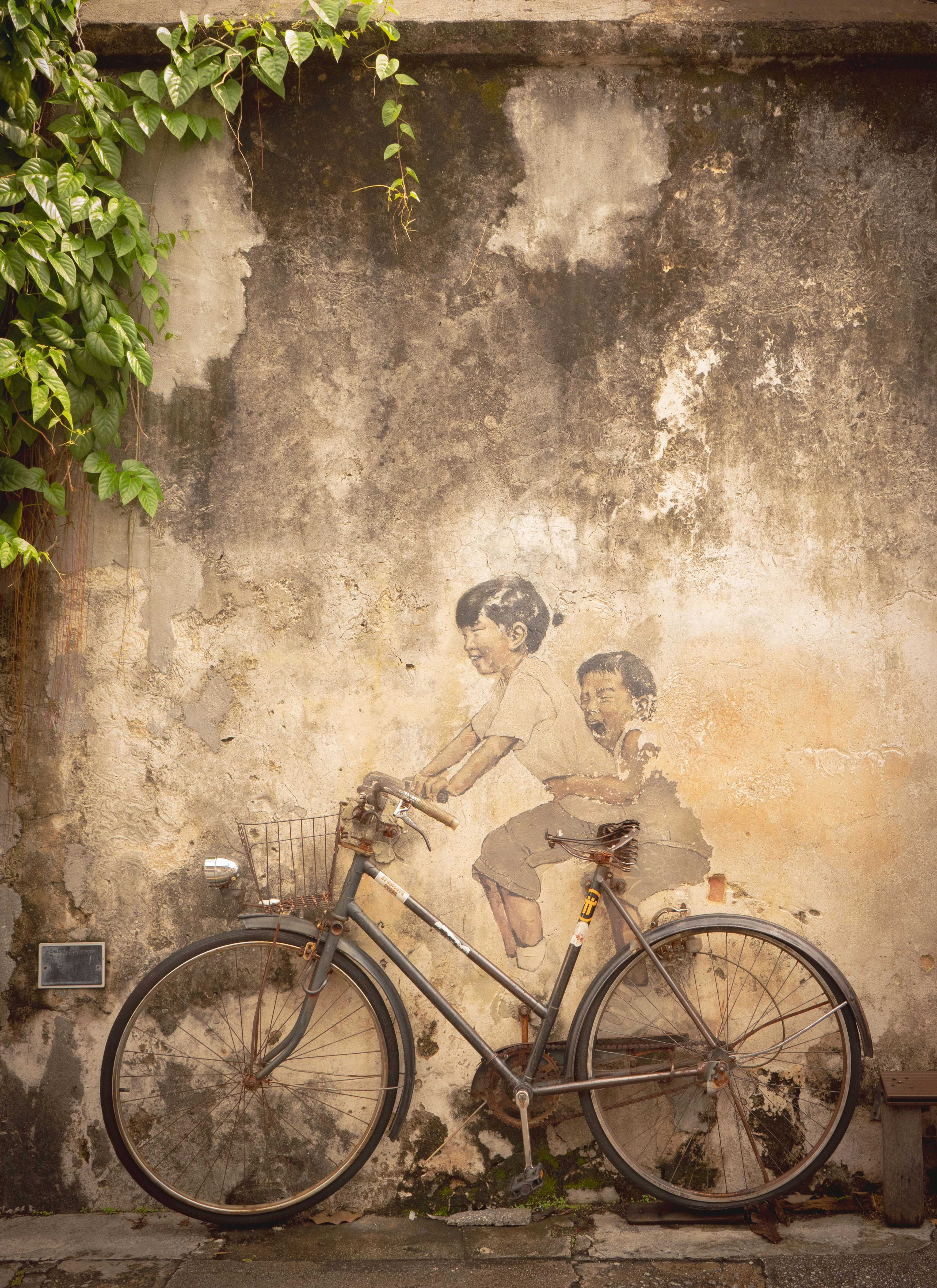 a bicycle parked next to a wall with a painting on it