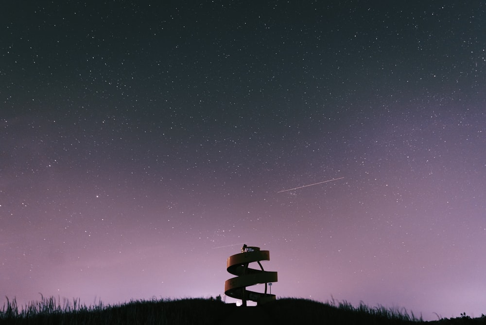 a wooden sign sitting on top of a hill under a night sky