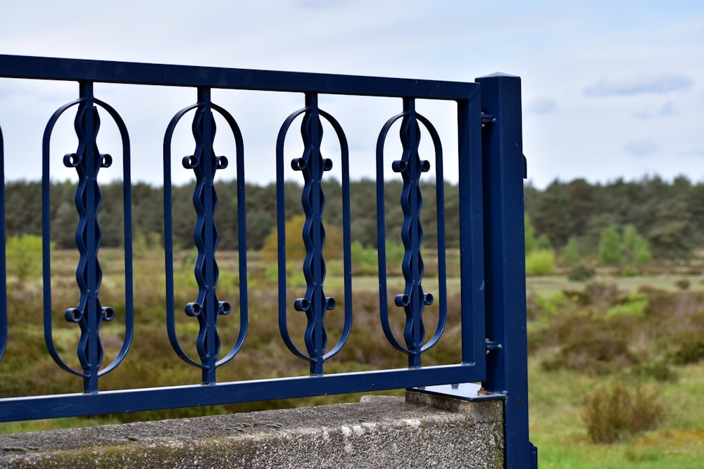 a metal fence with a grassy field in the background