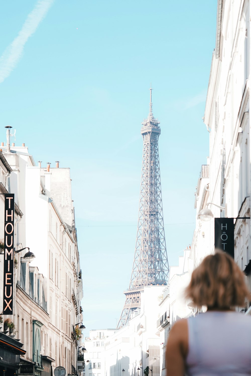 a woman walking down a street in front of the eiffel tower