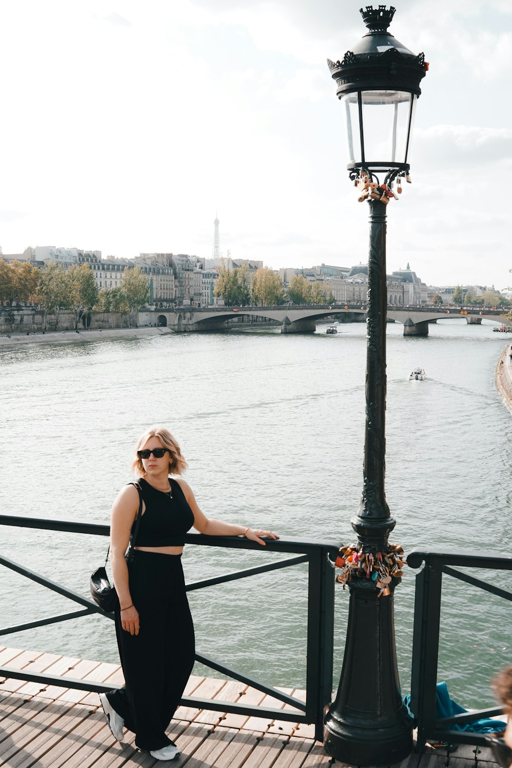 a woman standing on a bridge next to a lamp post