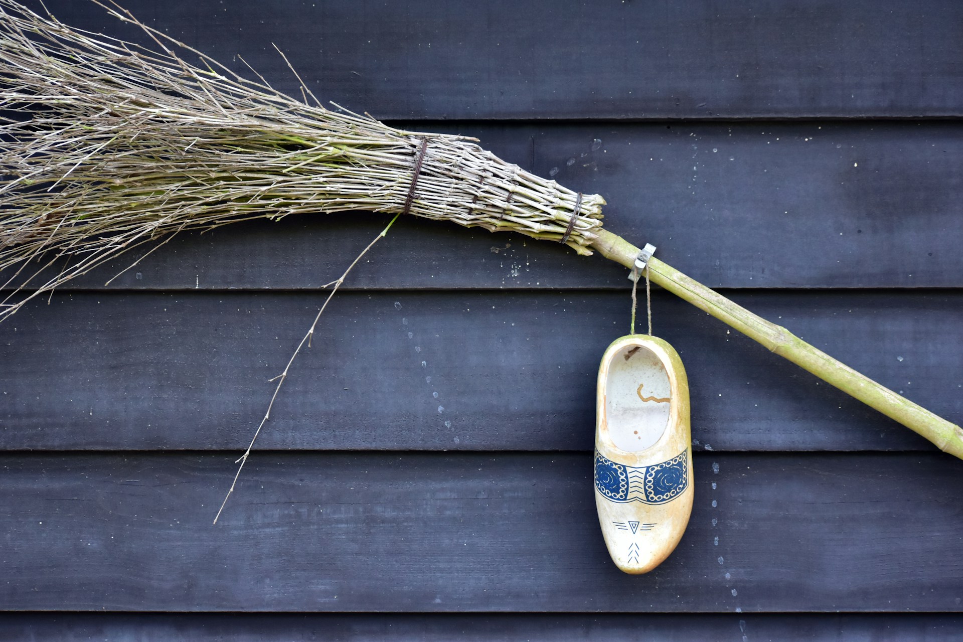 a pair of shoes hanging on a wall next to a broom
