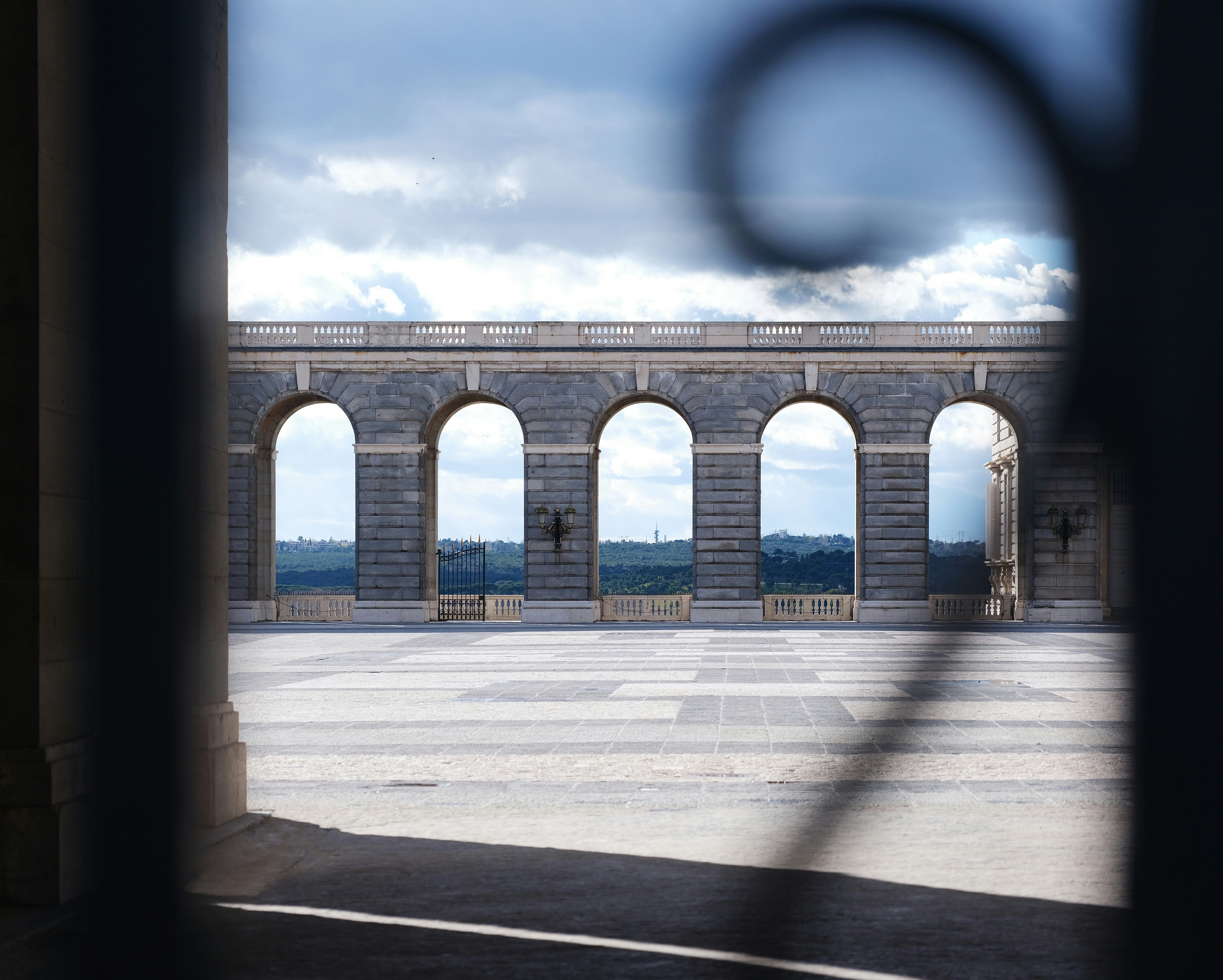 a stone wall with arches and a clock tower in the background